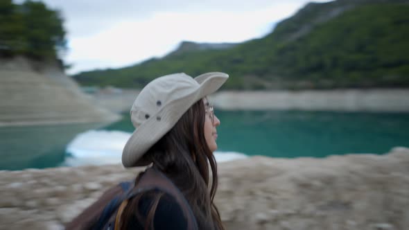 Girl with Backpack Hikes By Still Lake and Takes Out Phone Follow Pan