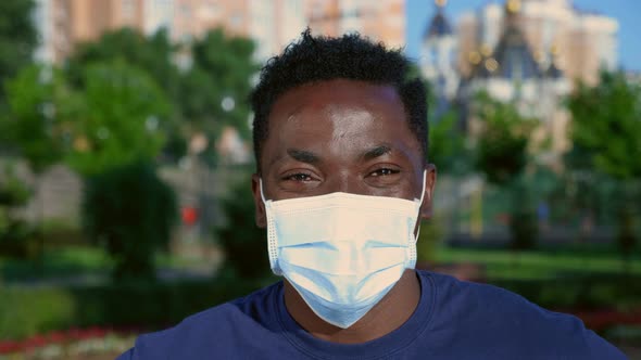 Close Up Smiling AfroAmerican Man in Protective Medical Face Mask Looks Camera