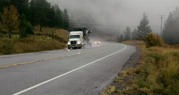 Service vehicles drives by on a foggy highway in Bella Coola BC.