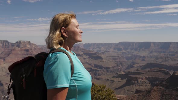 Female Tourist Stands At The Top Of Grand Canyon Inhaling Clean Fresh Air