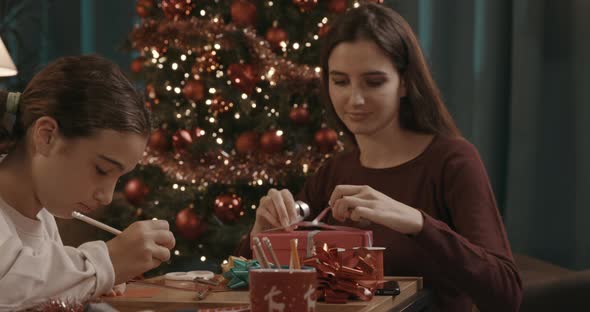 Sisters preparing Christmas gifts and writing cards together at home