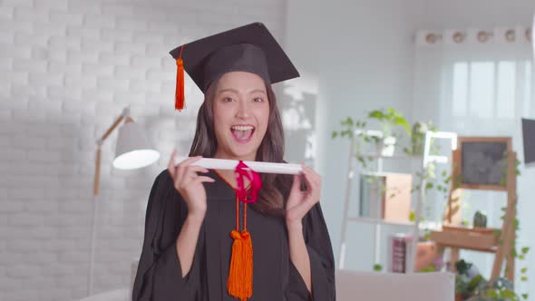 An Asian girl proudly shows her certificate. She is always smile on her graduation ceremony