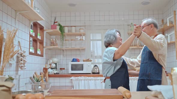 Asian Grandfather hug grandmother dance together, enjoy retirement life in kitchen after cook foods