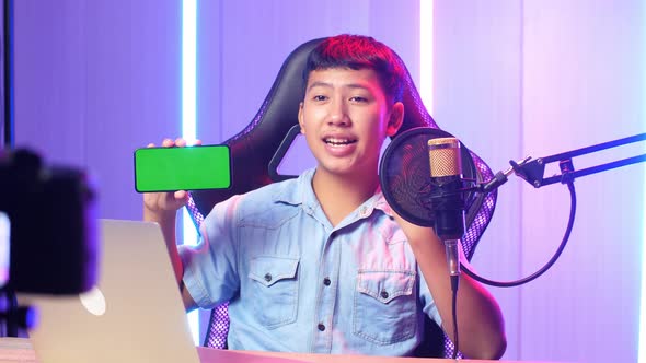 Asian Kid Boy Holding Mobile Phone With Mock Up Green Screen While Live Stream
