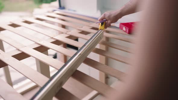 Close up shot of worker in van measuring wood with measuring tape during sunny day