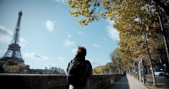 Tourist Girl with a Backpack Walks the City of Paris, Past the Eiffel Tower and the Seine River, and