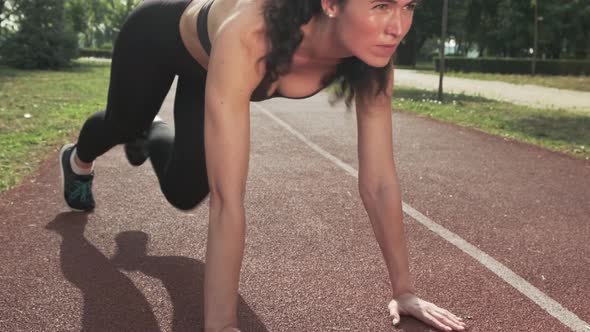 Young Woman Does Running Plank on Track Stadium Outdoors