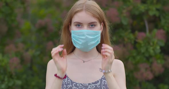 Beautiful young blonde girl takes off a medical mask