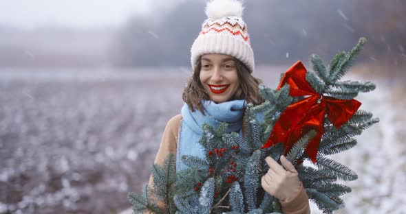 Woman with Christmas Branch on the Snowy Field