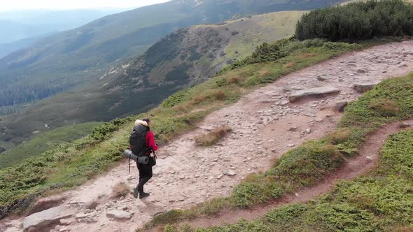 Aerial View of a Traveler Photographer with Backpack Climbing By Mountain Range