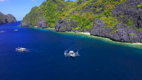 Aerial Drone View of White Traditional Filipino Boat Floating on Top of Clear Blue Water Surface