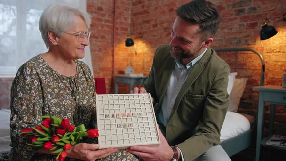 Mother's Day Plate Held By Middleaged Millennial Son and His Moved Elderly Mother