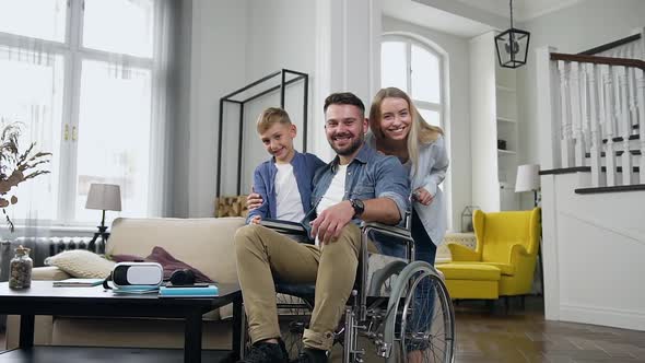 Young Mother, Father in Wheelchair and their Son Which Posing on Camera