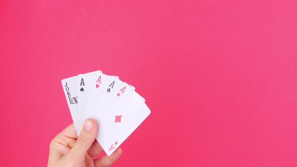 Five of a kind Poker Game cards in gambler hand falling money bills pink background