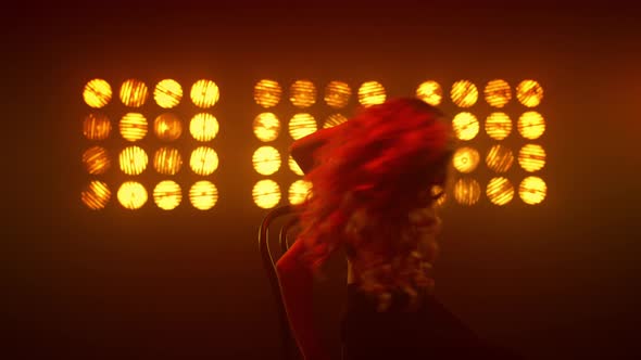 Passionate Woman Shaking Hair Performing Erotic Dance on Chair Nightclub