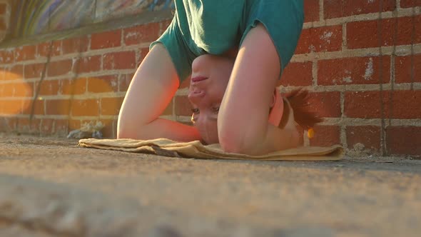 A young woman doing a headstand on the streets on an urban environment.