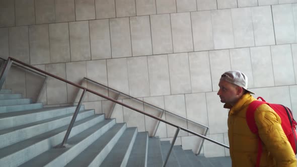 A Young Man Walks Up the High Stairs at the Large Building