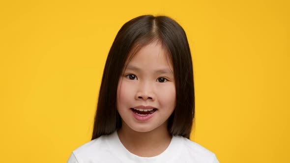 Portrait Of Adorable Asian Preschool Girl Posing Over Yellow Background