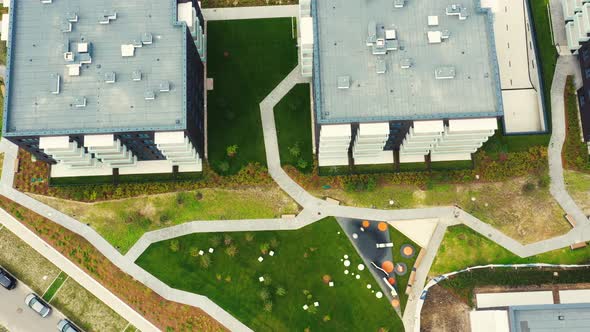 Drone overhead push down Shot of area in the middle of a residential building with cars, children's