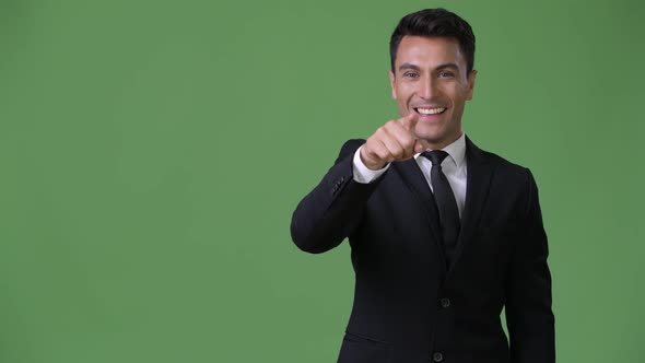 Young Handsome Hispanic Businessman Against Green Background