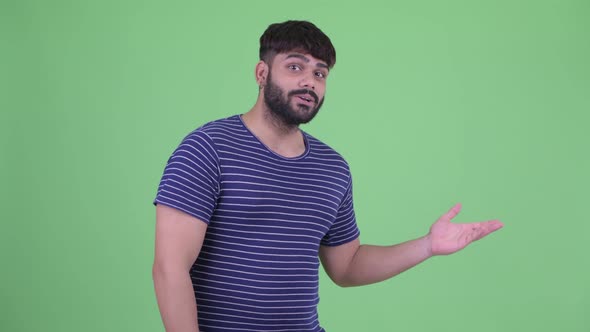 Happy Young Overweight Bearded Indian Man Presenting Something