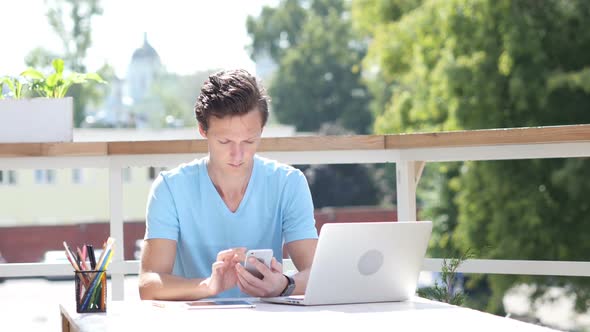 Sunny Day, Using Smartphone while Sitting Outdoor at Work