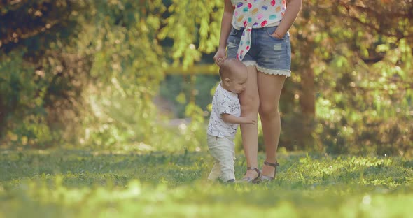 Little Boy Walks Across the Lawn in the Park and Holds His Mother By the Hand