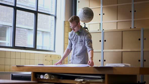 Male architect looking at blueprints in office