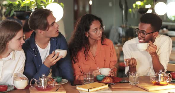 Four Multiethnic Friends Drinking Tea and Talking While Having Lunch, Cheerful Young Students