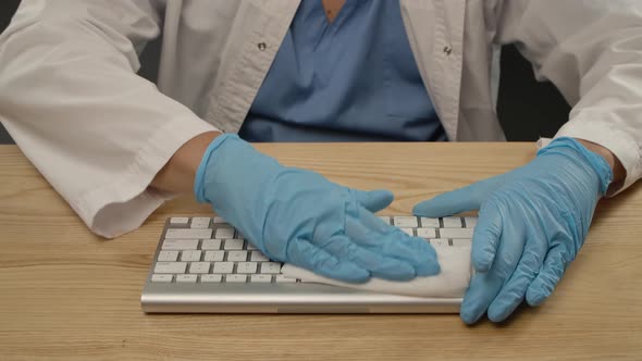 A Person Wearing Blue Protective Gloves and a White Coat Uses a Damp Antibacterial Cloth To Remove