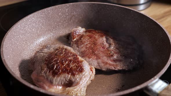 Two Juicy Beef Steaks Are Fried in a Pan Slow Motion