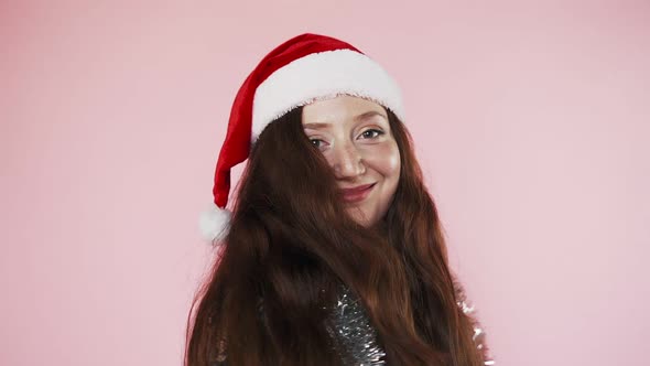 Beautiful red-haired Caucasian girl in Santa Claus hat. Christmas mood and Christmas.