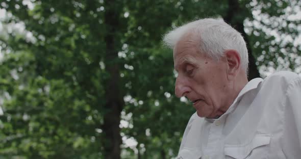 Profile View of Elder Man Speaking to Somebody on Leisure Outdoors in Summertime