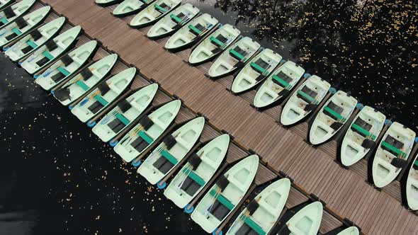 Aerial View of a Wooden Pier with Boats on a Lake with Autumn Foliage in a City Park