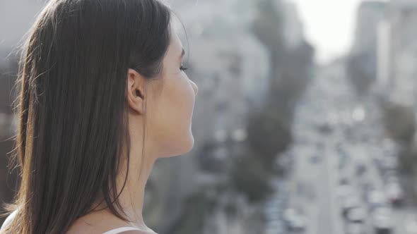 Young Woman Smiling To the Camera Over Her Shoulder While Observing Busy City