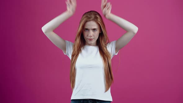 The Irritated Young Woman Puts Her Hands to Her Head in the Form of Horns and Looks Frustrated Ahead