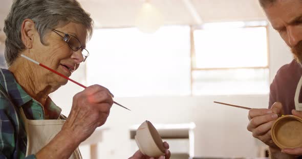 Male and female potter painting pots