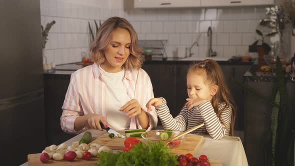Family Mother and Her Daughter Have Fun Preparing Vegetable Salad at Home in the Kitchen