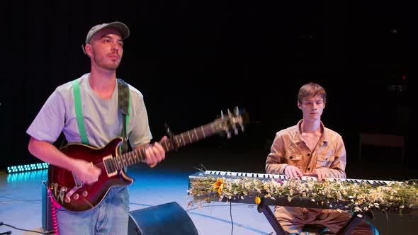 The Guitarist and Keyboardist Play on a Stage Illuminated By Blue Light