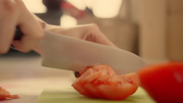 Woman cuts ripe tomato with sharp knife