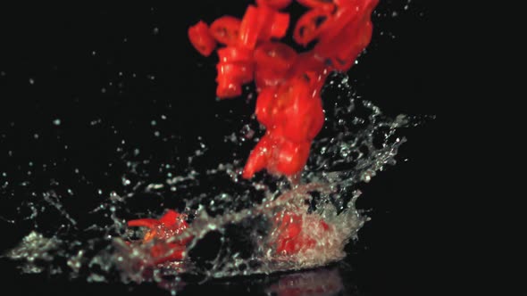 Super Slow Motion Chopped Chilli Pepper Falls on the Water with Splashes