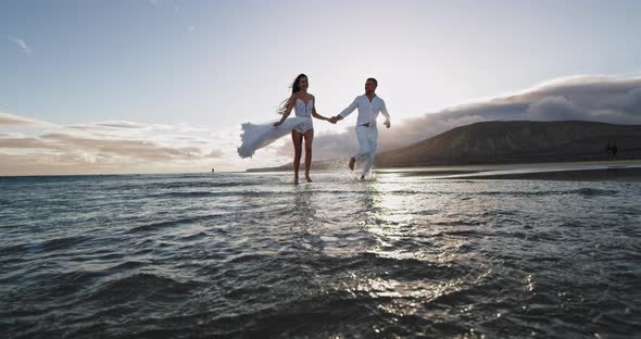 Running Couple Through the Sea Water Beside the