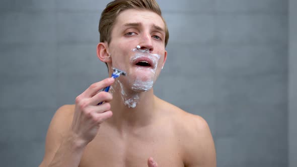 Young Caucasian Man with Foam on His Face Shaving with a Razor Millennial Man Taking Care of Stubble