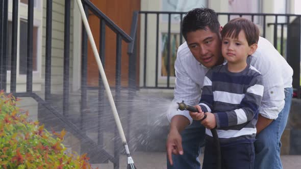 Father and son watering plants in yard