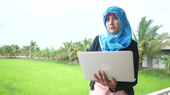 Arab woman standing typing laptop outdoor