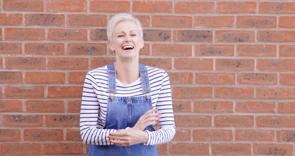 Woman with arms crossed standing in front of brick wall