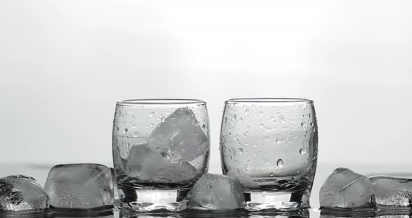 Pouring Up Two Shot of Vodka From a Bottle Into Glass. White Background
