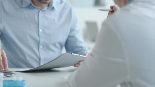 Man Signing Medical Service Agreement with Male Doctor