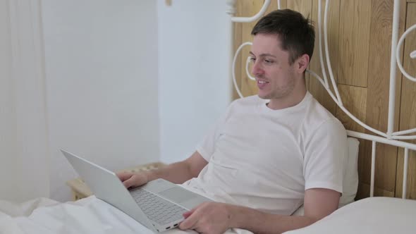 Young Man Online Video Chat on Laptop in Bed