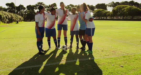 Female soccer team standing arm to arm on soccer field. 4k